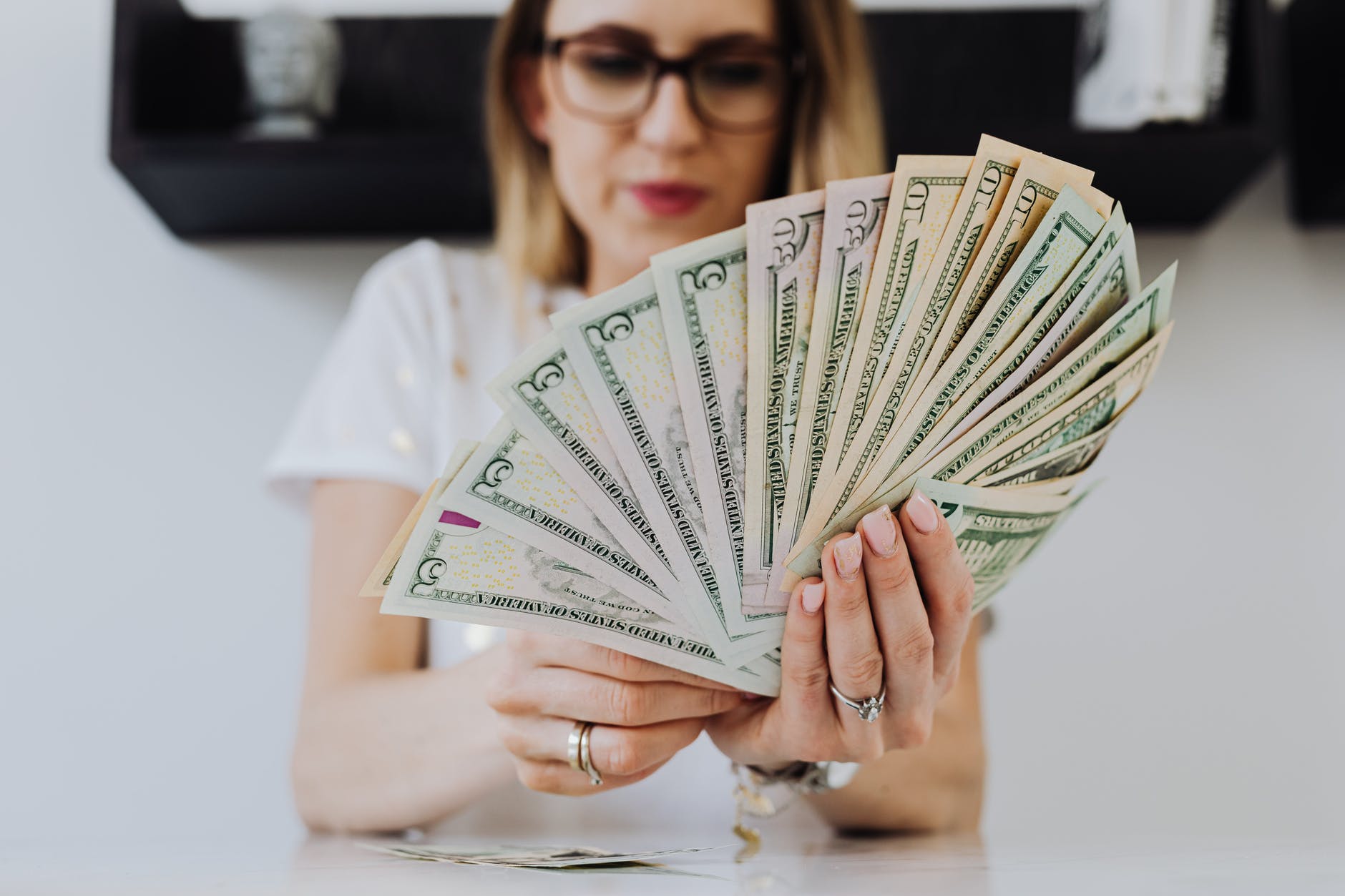 woman holding fan of us dollar bills